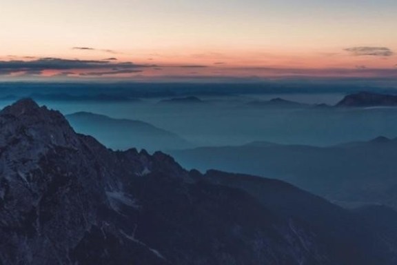 a sunset over a snow covered mountain
